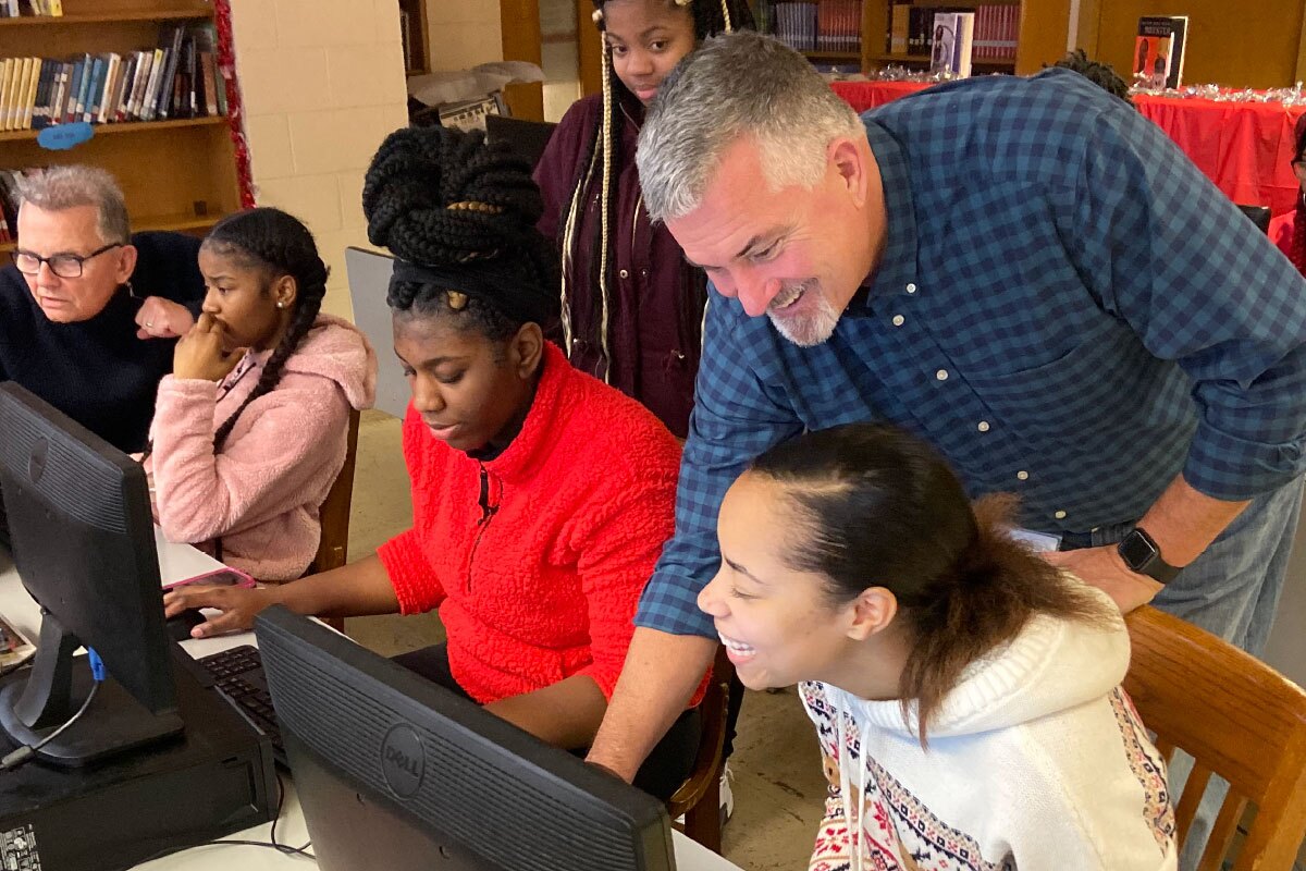 Coach showing something in computer to student